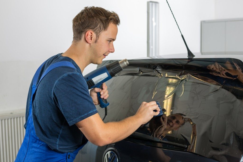 Worker applying a tint film on a car window