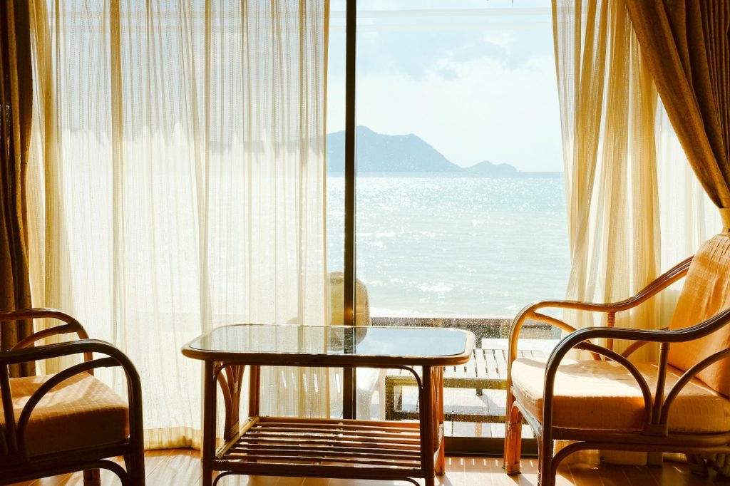 coffee table and chairs beside a glass window overlooking the sea