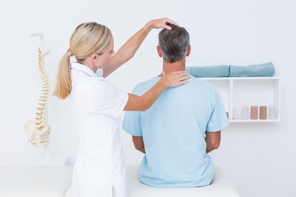 Doctor checking neck in medical office