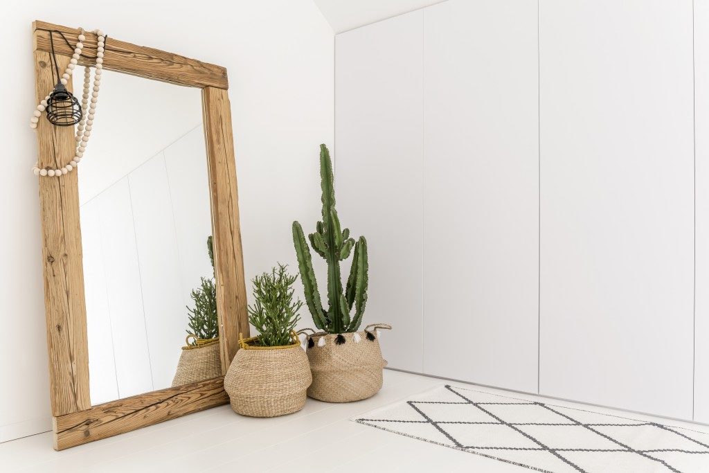 white room with wooden full-sized mirror and plant on baskets