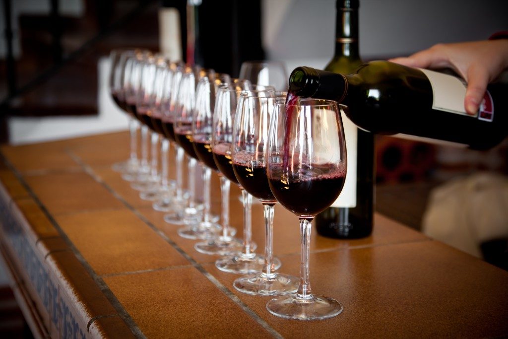 wine bottle pouring a row of glasses for tasting