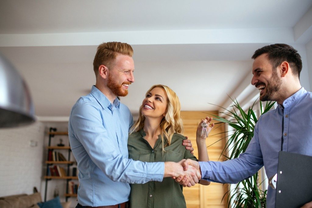 real estate agent shaking hands with couple