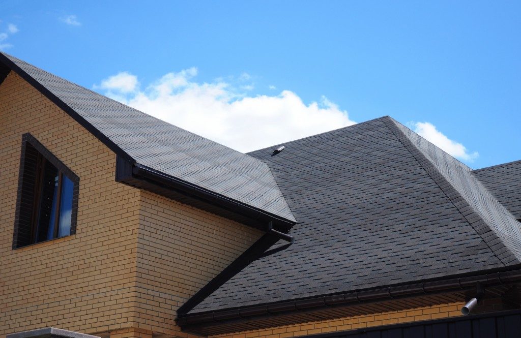 Grey roofing with black gutters and brick-wall house