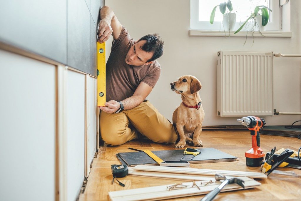 man doing construction work at home with his dog