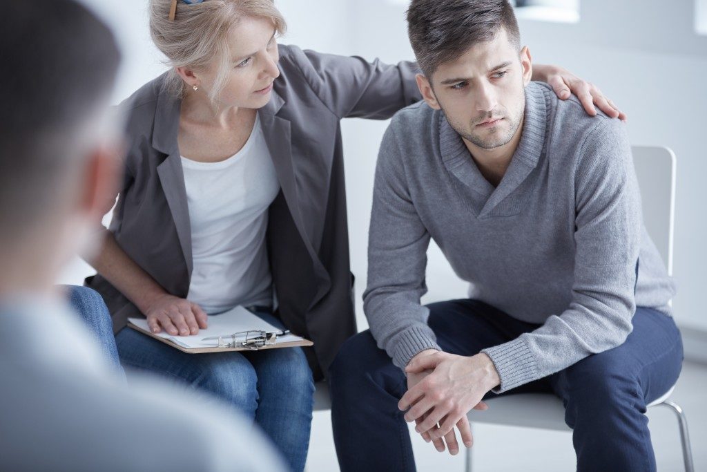 Caring psychotherapist supporting her young broken down patient