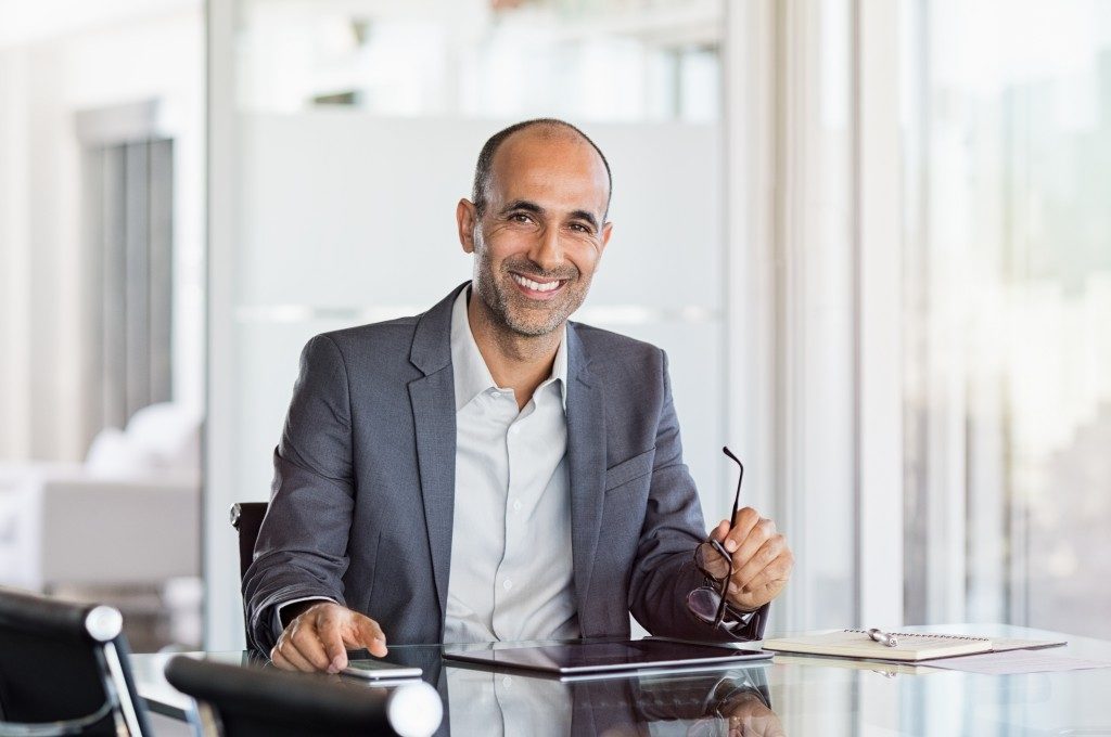 Business man holding glasses in modern office