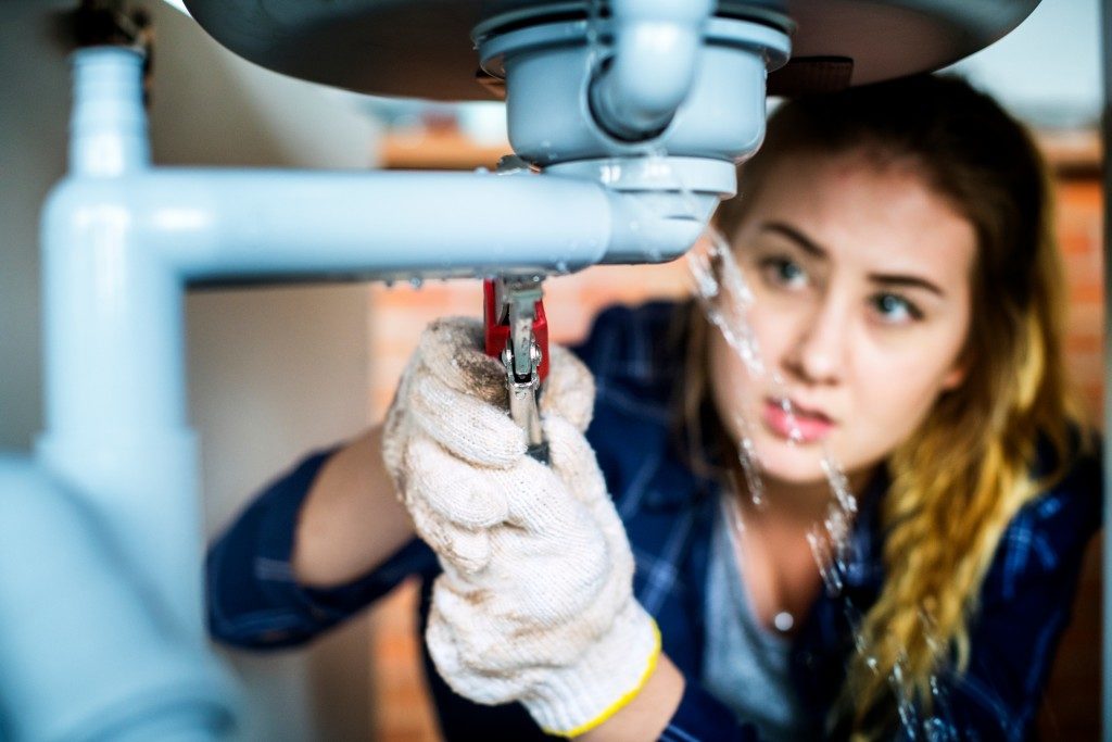 woman fixing a leaking pipe