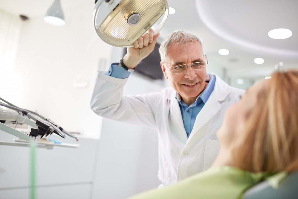 Senior male dentist adjusting the searchlight