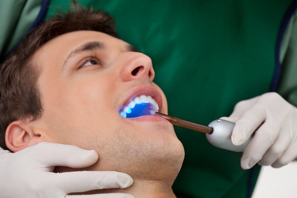 Patient having dental checkup with ultraviolet light at dentist's clinic