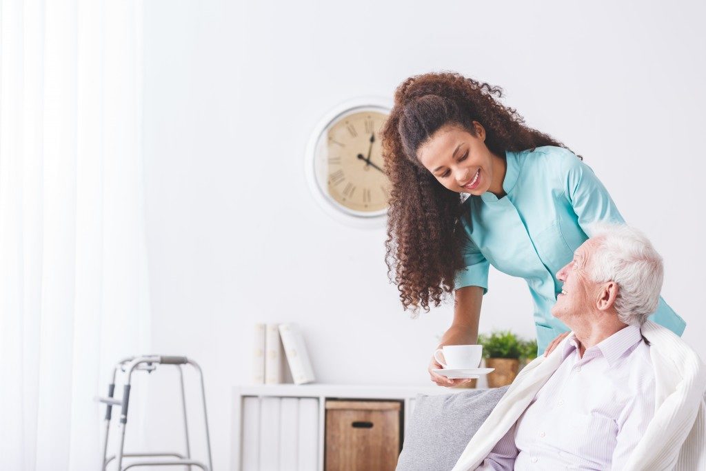 nursing staff serving tea to elderly man