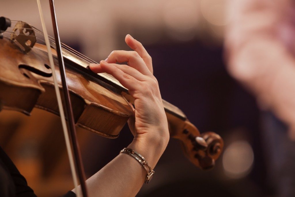 Hand on the strings of a violin