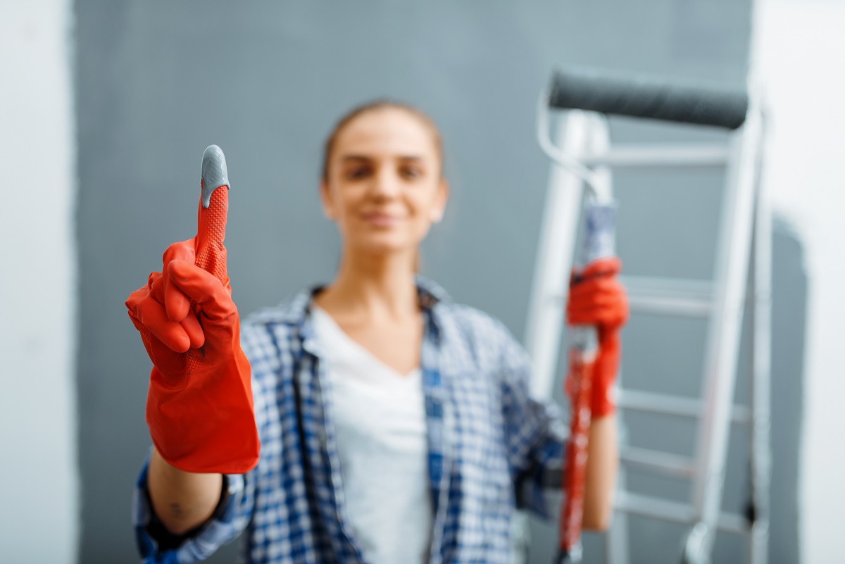 Young woman shows glove in paint, home repair