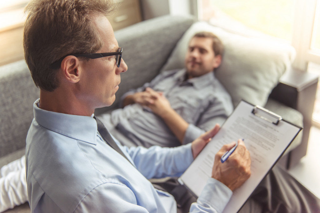 Man telling about his problems while lying on the couch at the psychotherapist