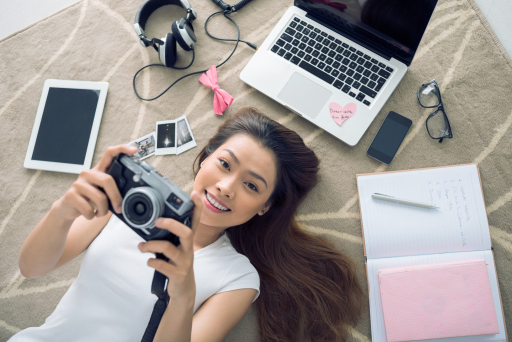 woman holding a camera along with her gadgets