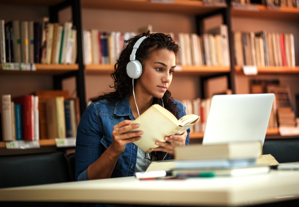 woman wearing headphones reading a book
