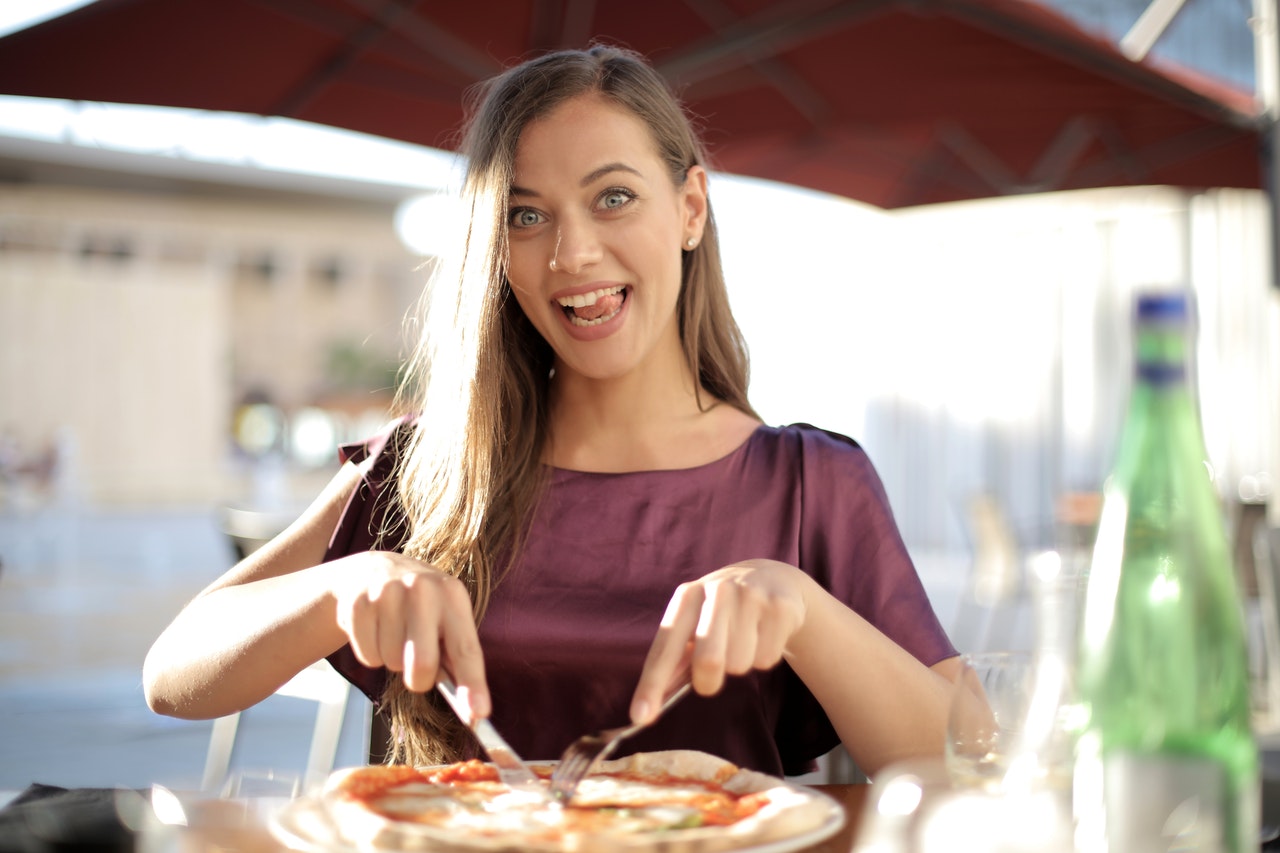 woman eating pizza outside