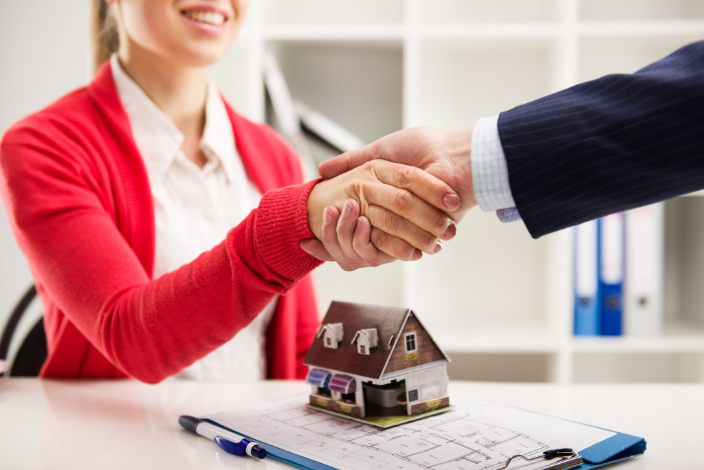 a man and woman are shaking hands to symbolize agreement of a mortgage loan