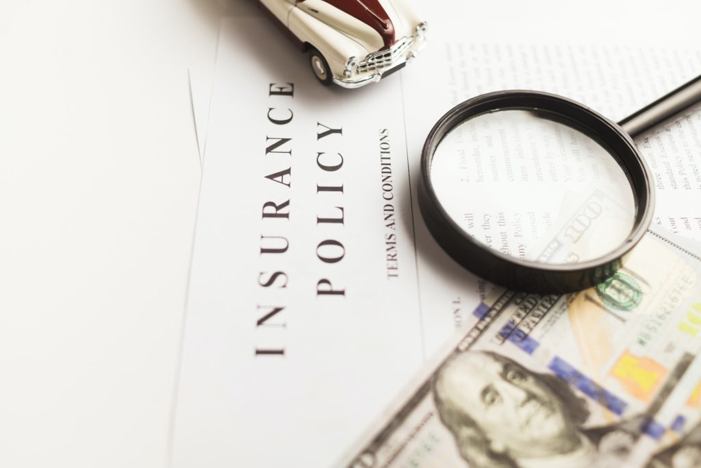 insurance policy document with magnifying glass and dollar bill